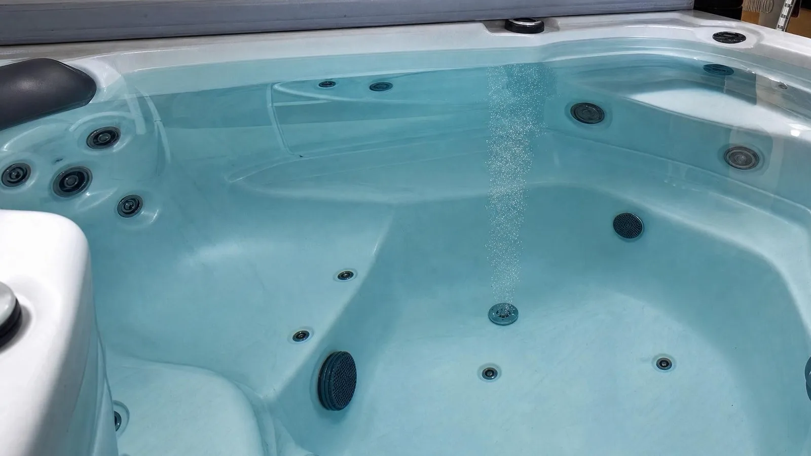 Fin filet de micro-bulles blanches qui remonte d'une buse dans l'eau claire d'un spa