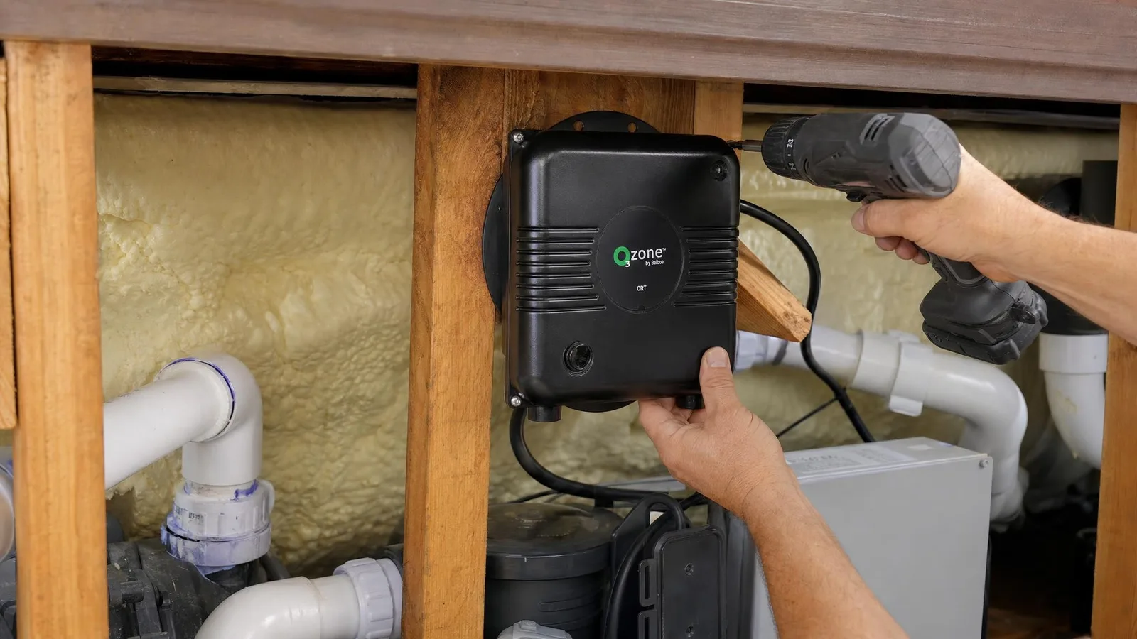 Ozonateur Balboa O3zone vissé sur un montant en bois du compartiment technique d'un spa, en hauteur